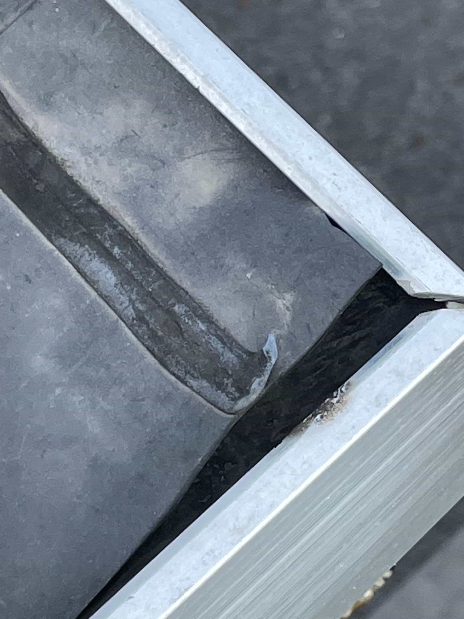 Detail van zinken dakgoot met beschadigde aansluiting