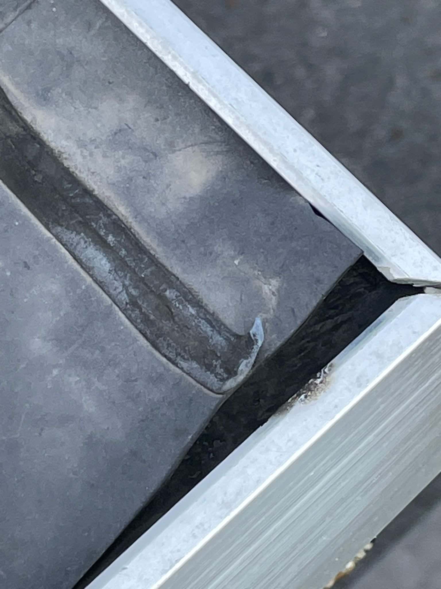 Detail van zinken dakgoot met beschadigde aansluiting
